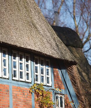 Ein Backsteinhaus mit Strohdach und blauen Verzierungen