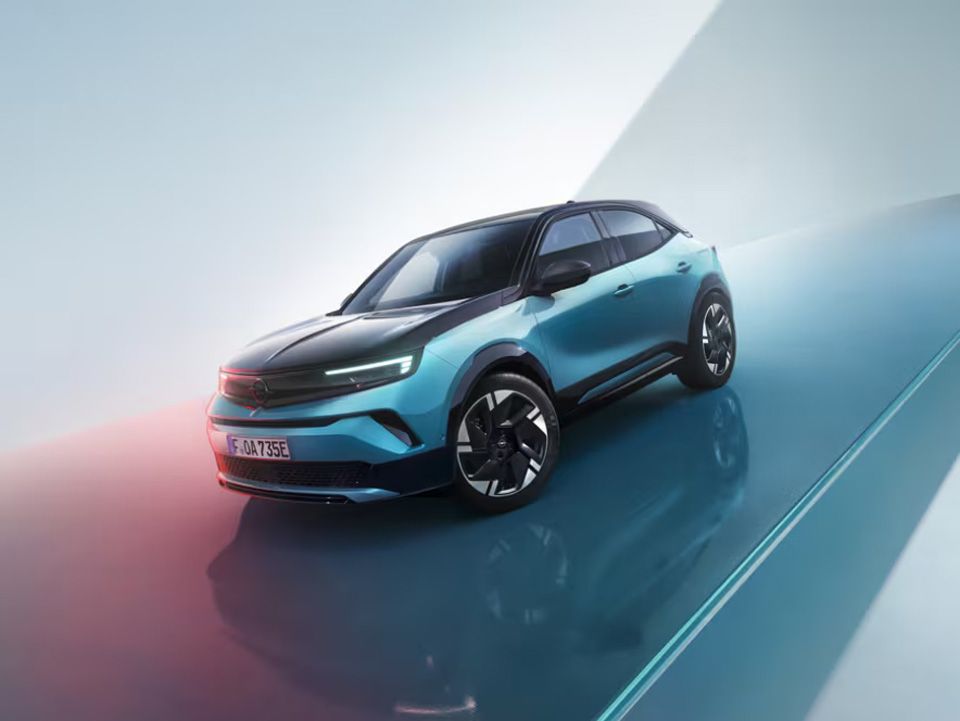 SUV Opel Mokka bleu sur une surface réfléchissante sur fond dégradé bleu clair et blanc.