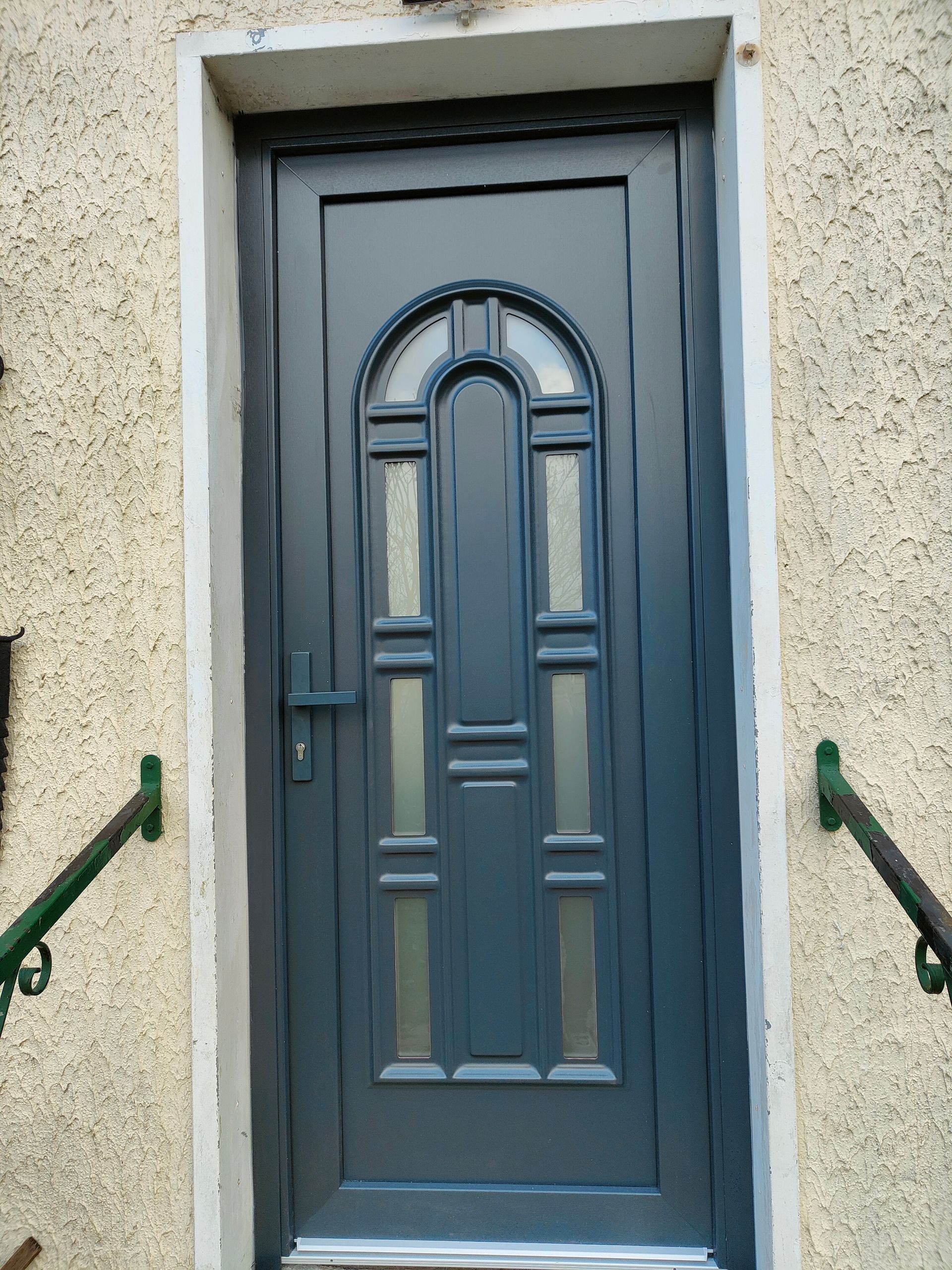 Une porte d'entrée grise et en bois.