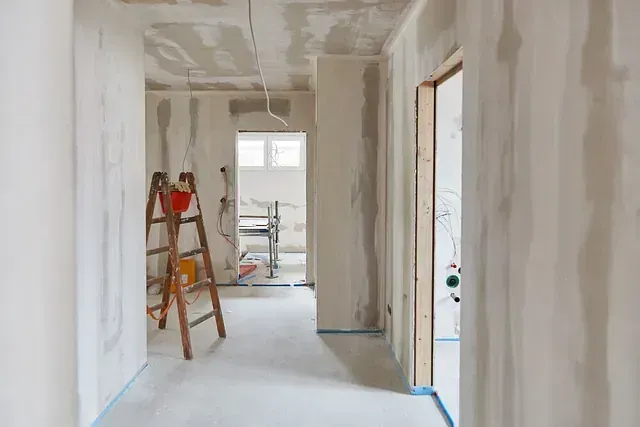 Un pasillo en una casa en construcción con una escalera en el suelo.