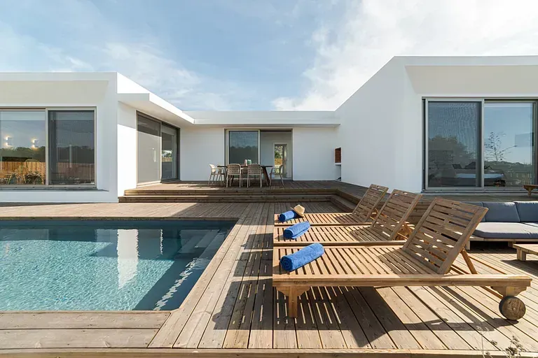 Una casa blanca con una gran piscina delante de ella.