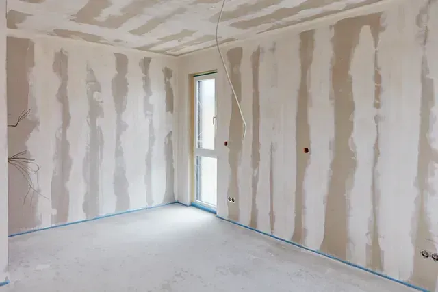 Una habitación vacía con paredes de yeso y una ventana.