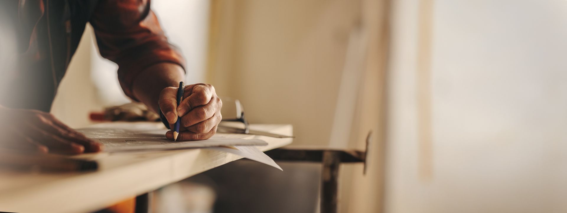 Une personne écrit sur une feuille à un bureau, près d'une lampe, dans une douce lumière chaude.