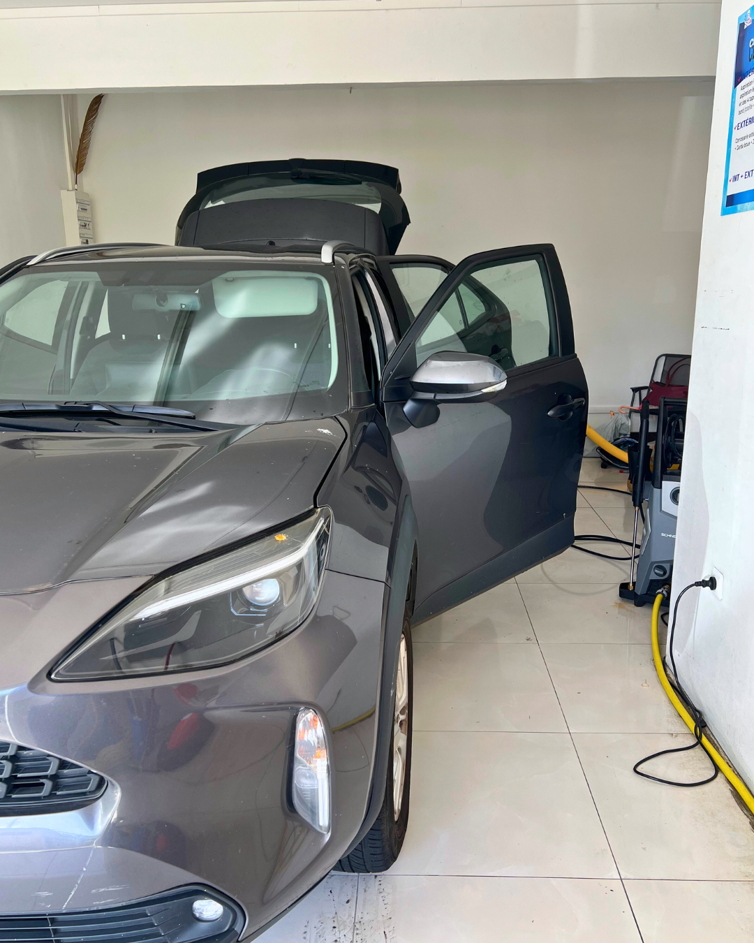 Voiture à hayon grise garée dans un garage, hayon arrière et portière passager avant ouverts.