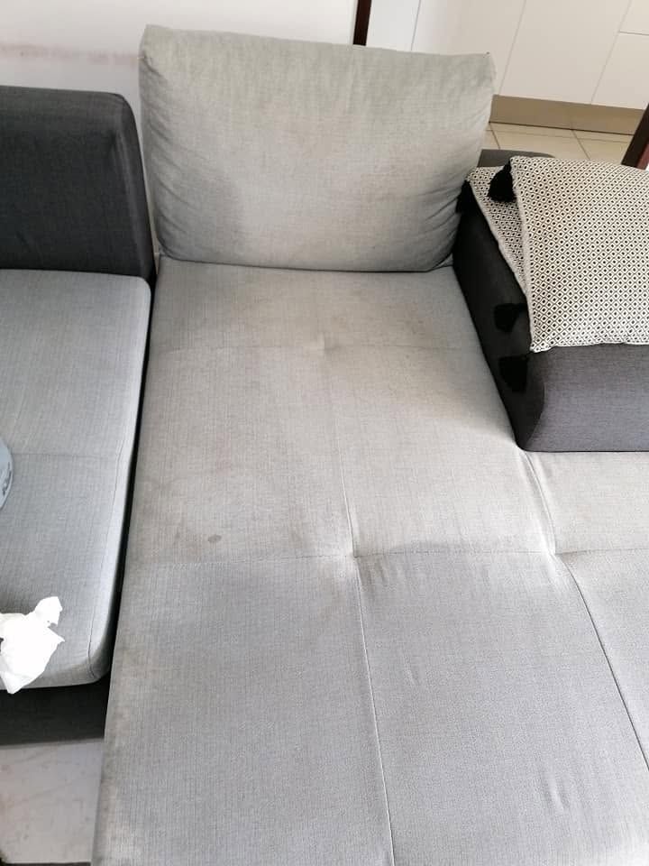 Coussins de canapé gris avec un plateau en osier sur l'accoudoir droit et un petit objet blanc sur le siège gauche.
