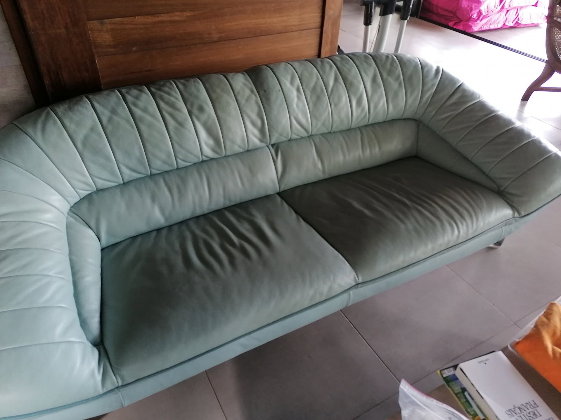 Canapé en cuir vert avec dossier et assise capitonnés, vu de dessus dans une pièce.