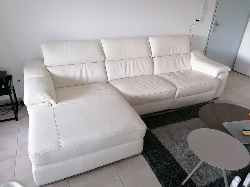 Canapé d'angle blanc avec méridienne dans un salon moderne, à côté d'une table basse en verre et d'un tapis gris