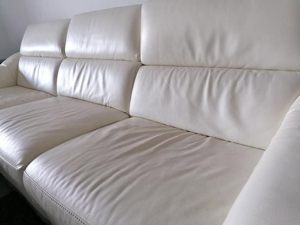 Canapé d'angle en cuir blanc avec coussins capitonnés dans une pièce lumineuse