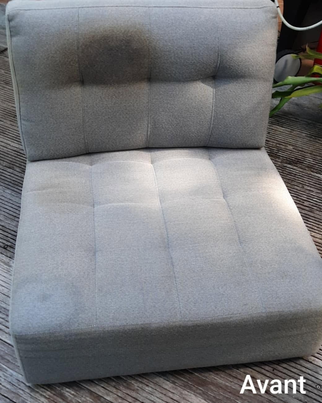 Coussin de chaise gris capitonné avant nettoyage, présentant des taches et des traces d'usure visibles.