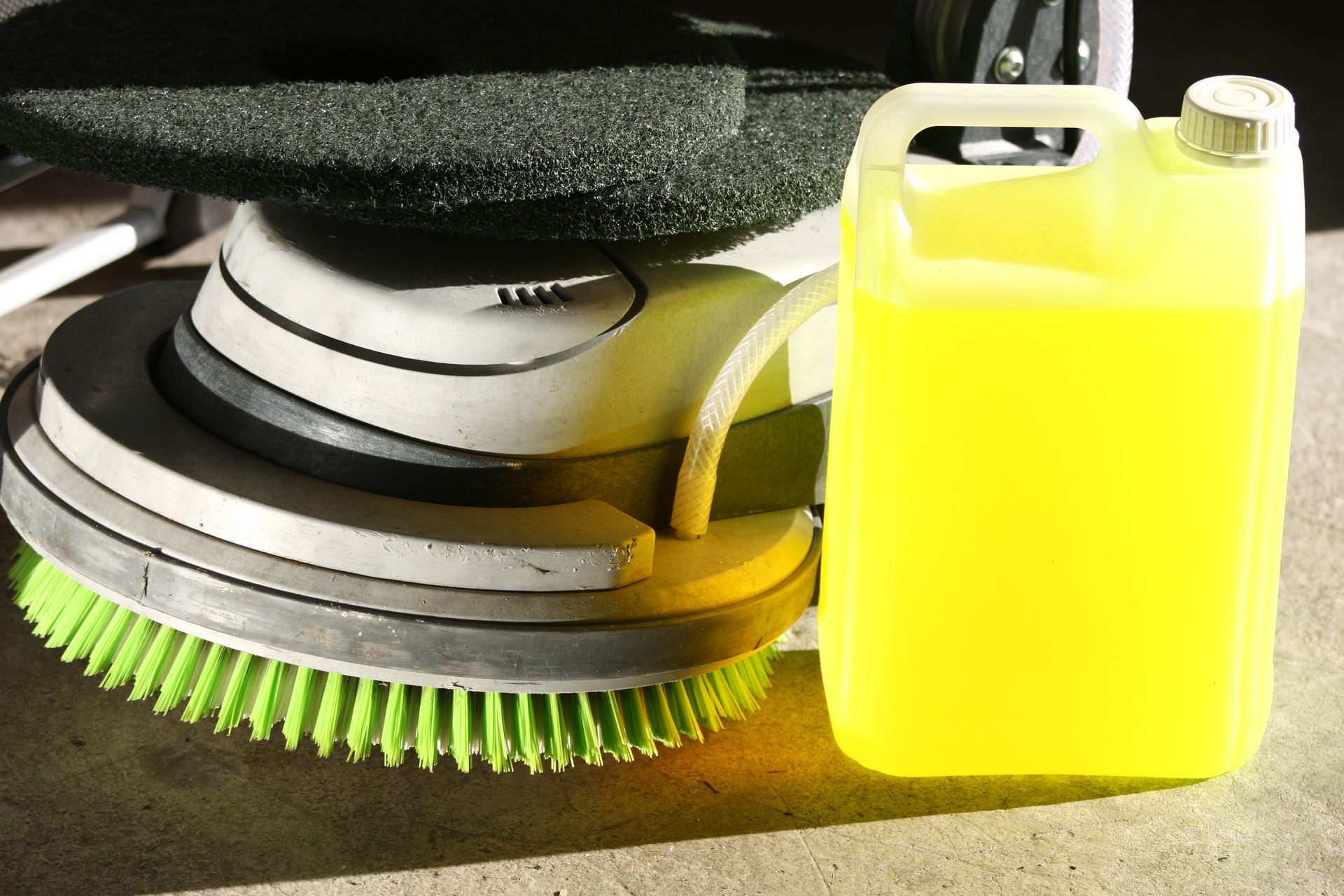 Machine de nettoyage à poils verts à côté d'un bidon en plastique jaune