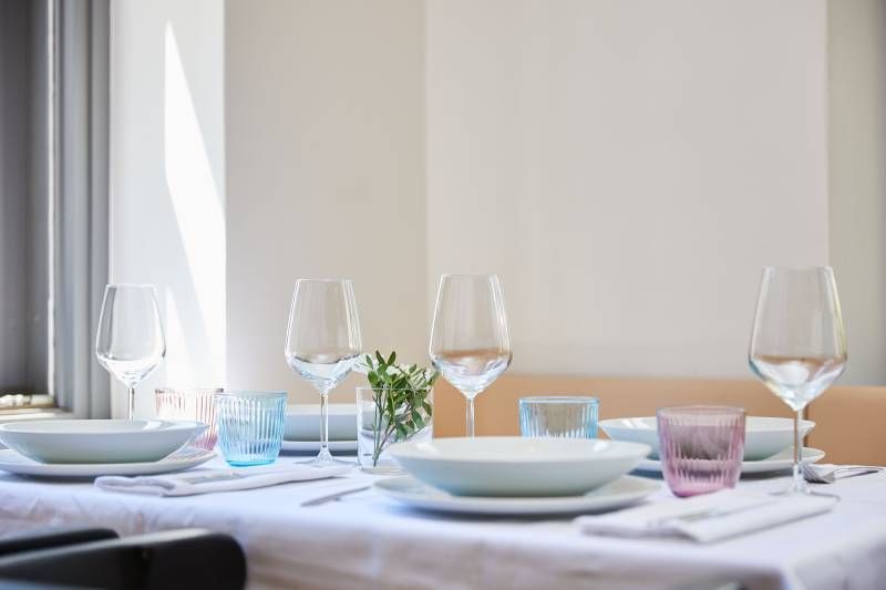 Une table dressée pour un repas avec des assiettes, des bols et des verres à vin.