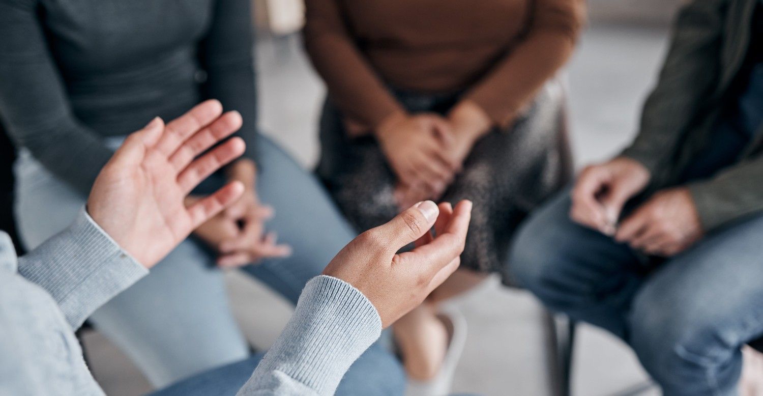 Personas sentadas en círculo durante una discusión, con una persona gesticulando mientras habla.
