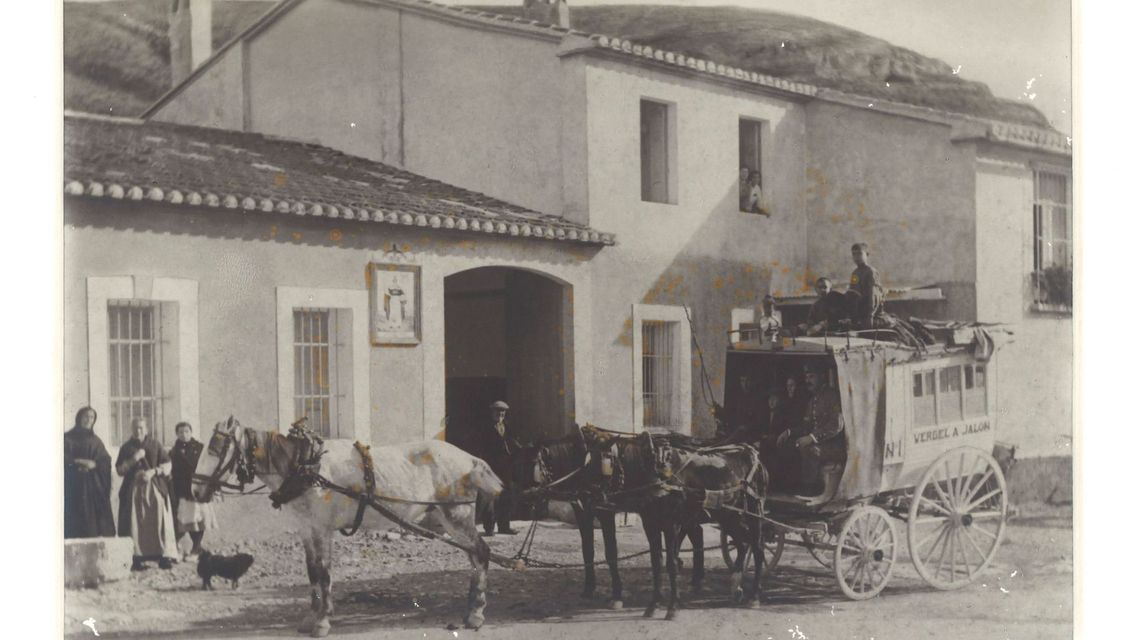 Un carruaje tirado por caballos está estacionado frente a un edificio.