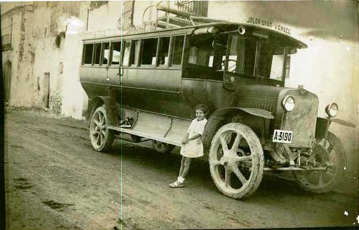 Una niña está parada al lado de un viejo autobús.