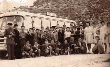 Un grupo de personas posa para una fotografía frente a un autobús.