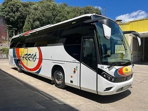 Un gran autobús blanco está estacionado al costado de la carretera.