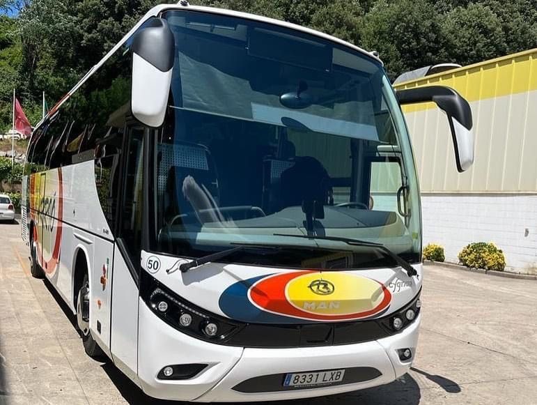 Un gran autobús blanco está estacionado frente a un edificio.