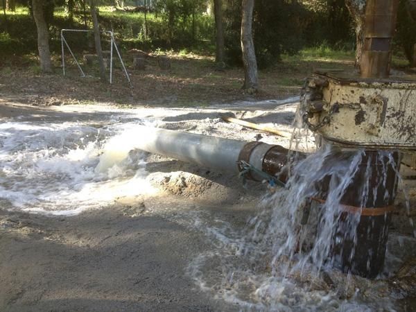 Sale agua de una tubería en el suelo.