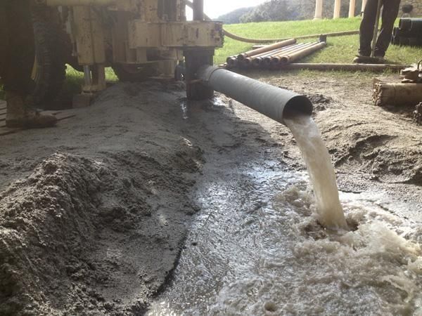 Una tubería vierte agua en un agujero en el suelo.