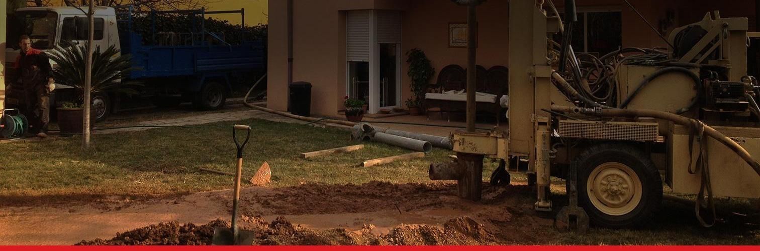 Un tractor está cavando un hoyo en la tierra frente a una casa.