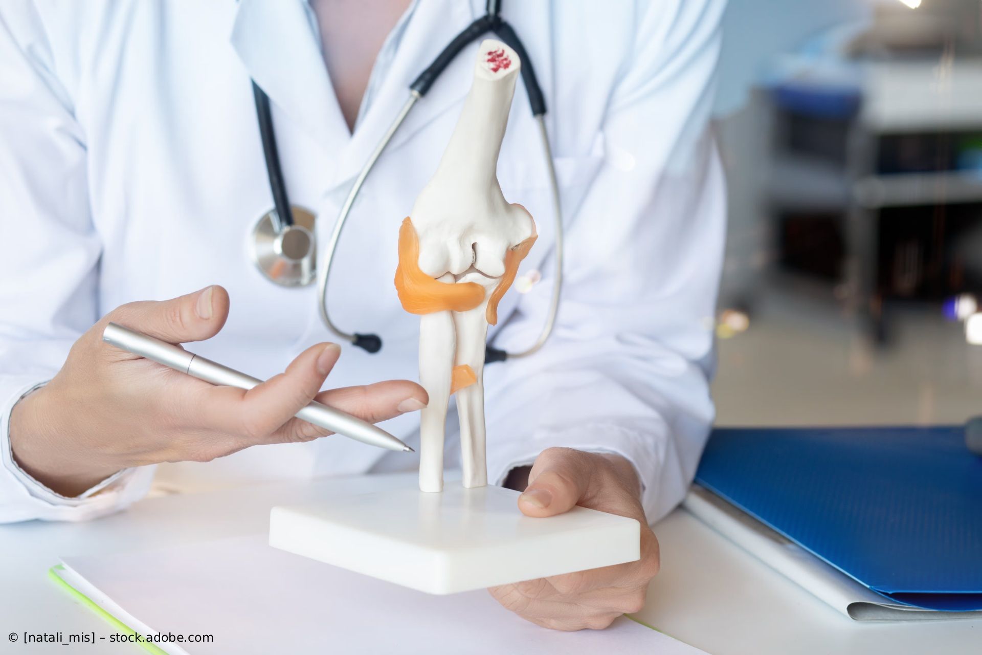 Ein Physiotherapeut dehnt das Bein eines Patienten auf einer Behandlungsliege in einem hellen Klinikraum.