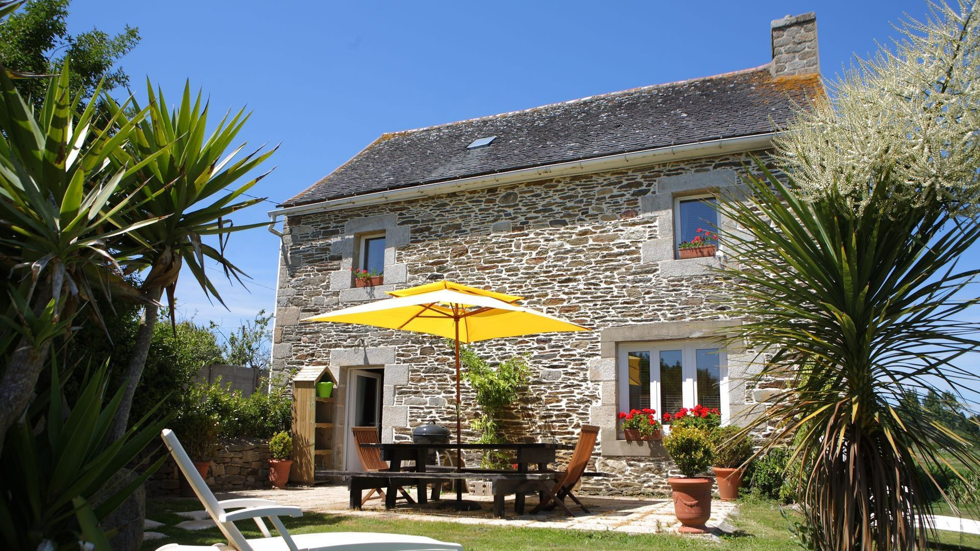 Maison en pierres avec un parasol jaune