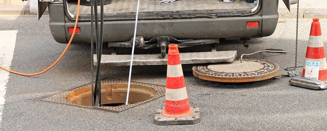Ein Lieferwagen steht neben einem Kanaldeckel am Straßenrand