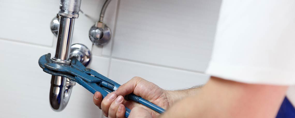 Ein Klempner repariert ein Waschbecken mit einem Schraubenschlüssel