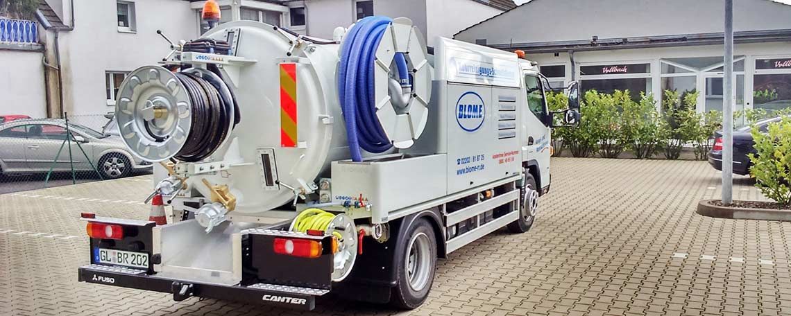 Ein weißer Saugwagen steht auf einem Parkplatz
