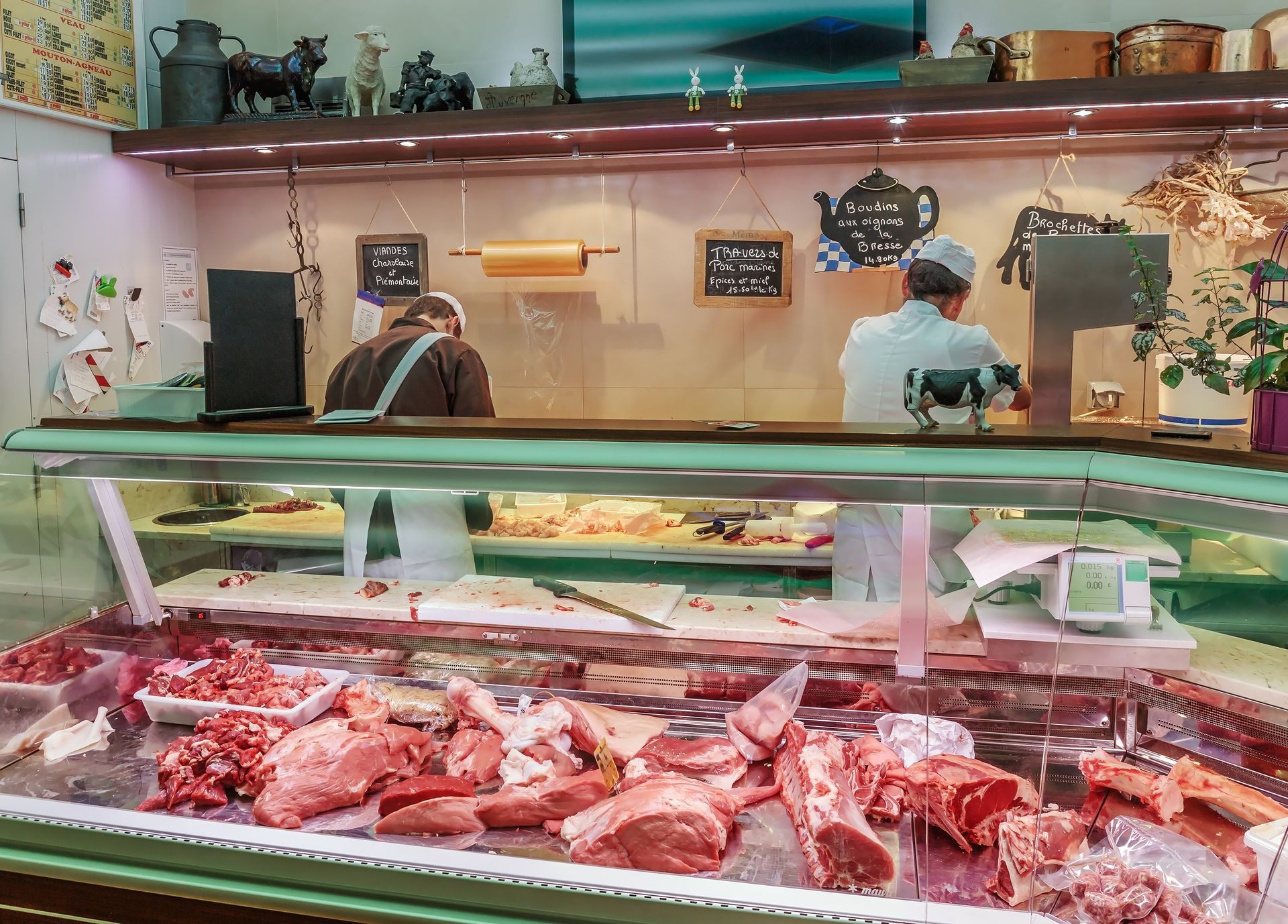 Vitrine de boucherie avec deux employés derrière un comptoir vitré