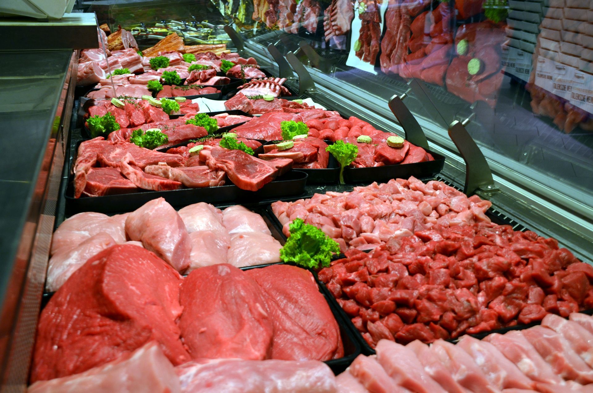 Présentoir de boucherie avec assortiment de morceaux crus de bœuf et de porc dans une vitrine réfrigérée