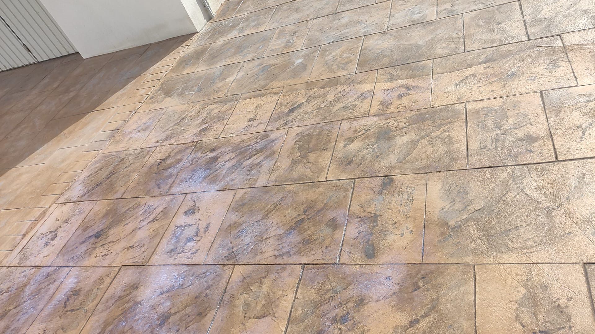 Suelo de baldosas color beige brillante con un patrón decorativo, visto desde un ángulo bajo dentro de una habitación.
