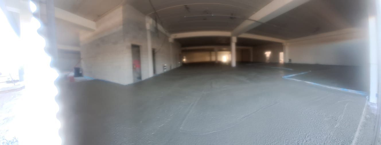 Interior vacío de un estacionamiento con pilares de hormigón y luz brillante en la entrada.