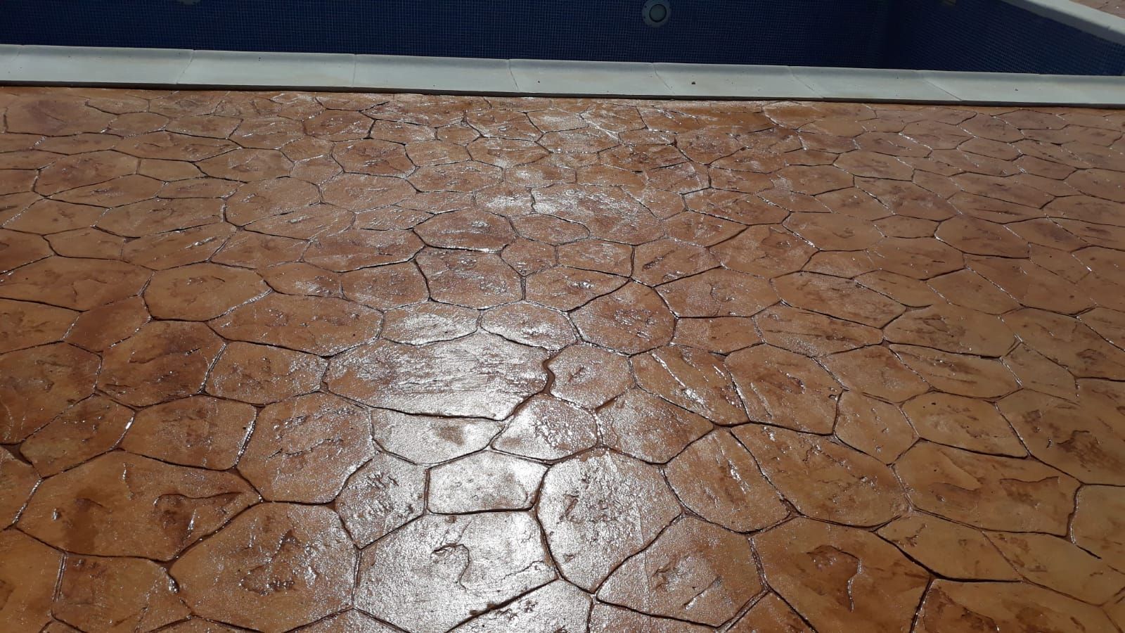 Suelo marrón agrietado con un brillo reflectante junto a una pared azul oscuro.