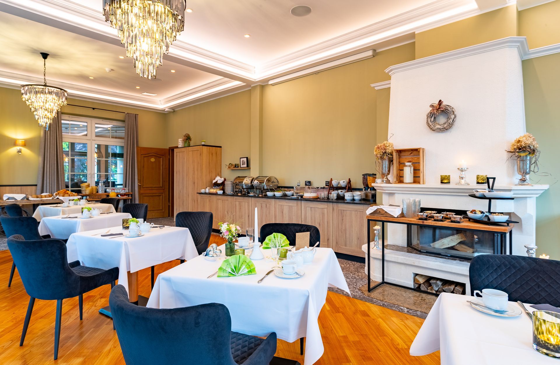 Eleganter Hotelfrühstücksraum mit gedeckten Tischen für Gäste, Buffet und Kamin.