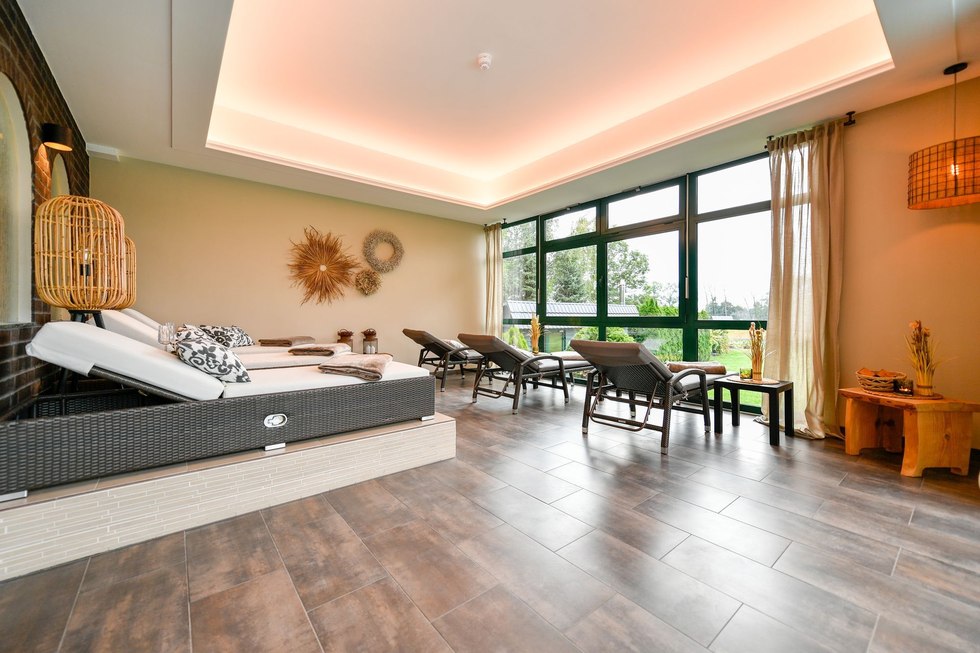 Ruheraum mit Liegestühlen, großen Fenstern und sanfter Beleuchtung.