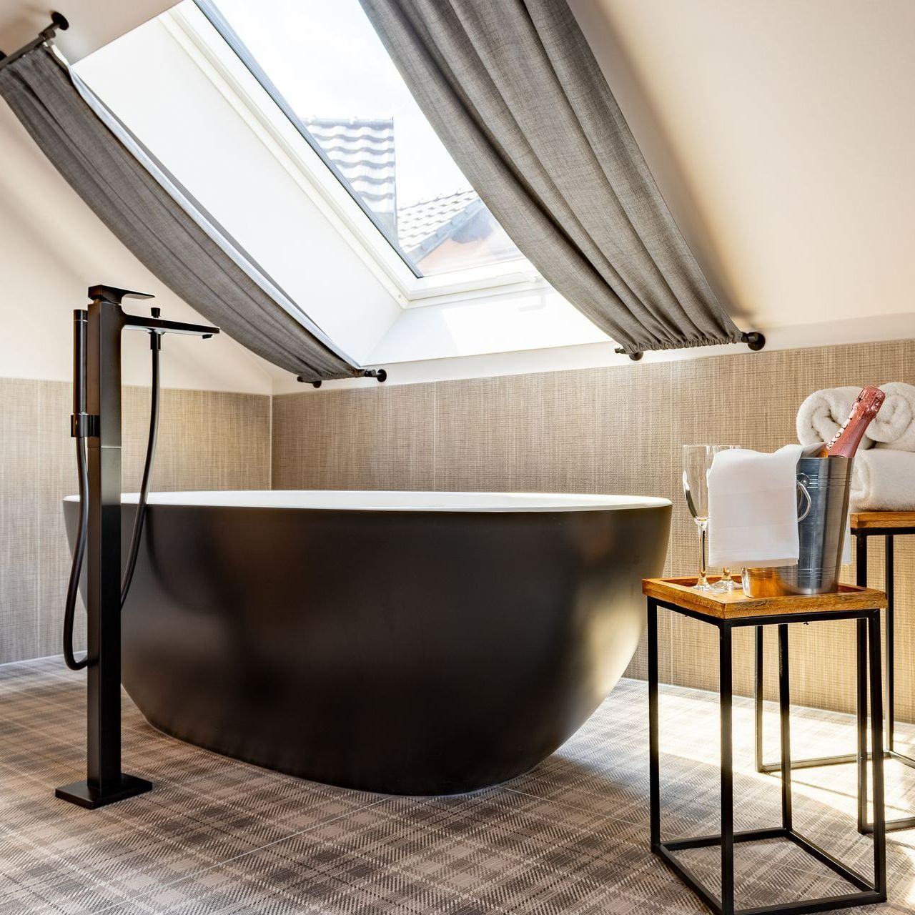 Schwarze Badewanne in einem Badezimmer mit Oberlicht, Champagner und Handtuch.