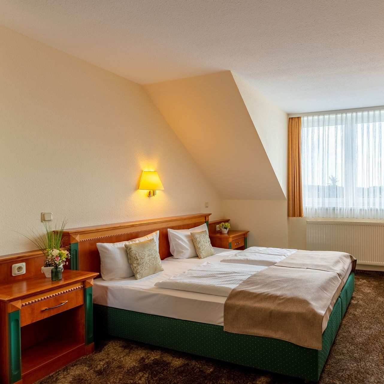 Hotelzimmer mit Doppelbett, Nachttischen und Fenster.