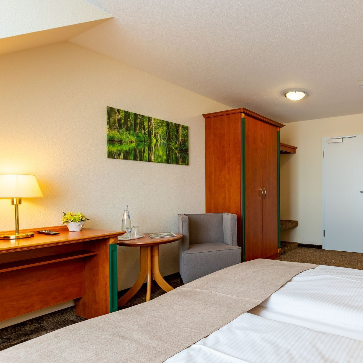 Hotelzimmer mit Bett, Schreibtisch, Stuhl und Kleiderschrank; Kunst an der Wand.