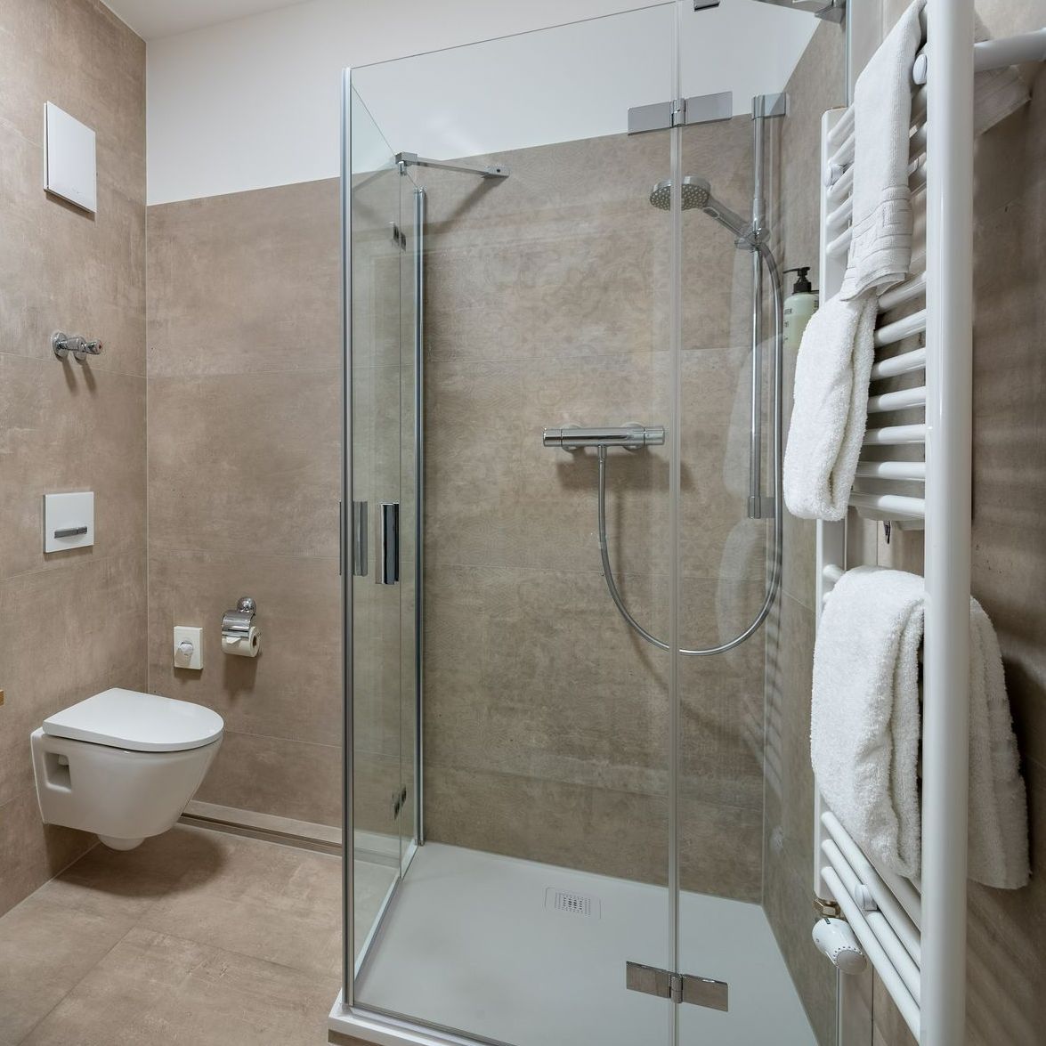 Modernes Badezimmer mit Glasdusche, Toilette und Handtuchhalter.