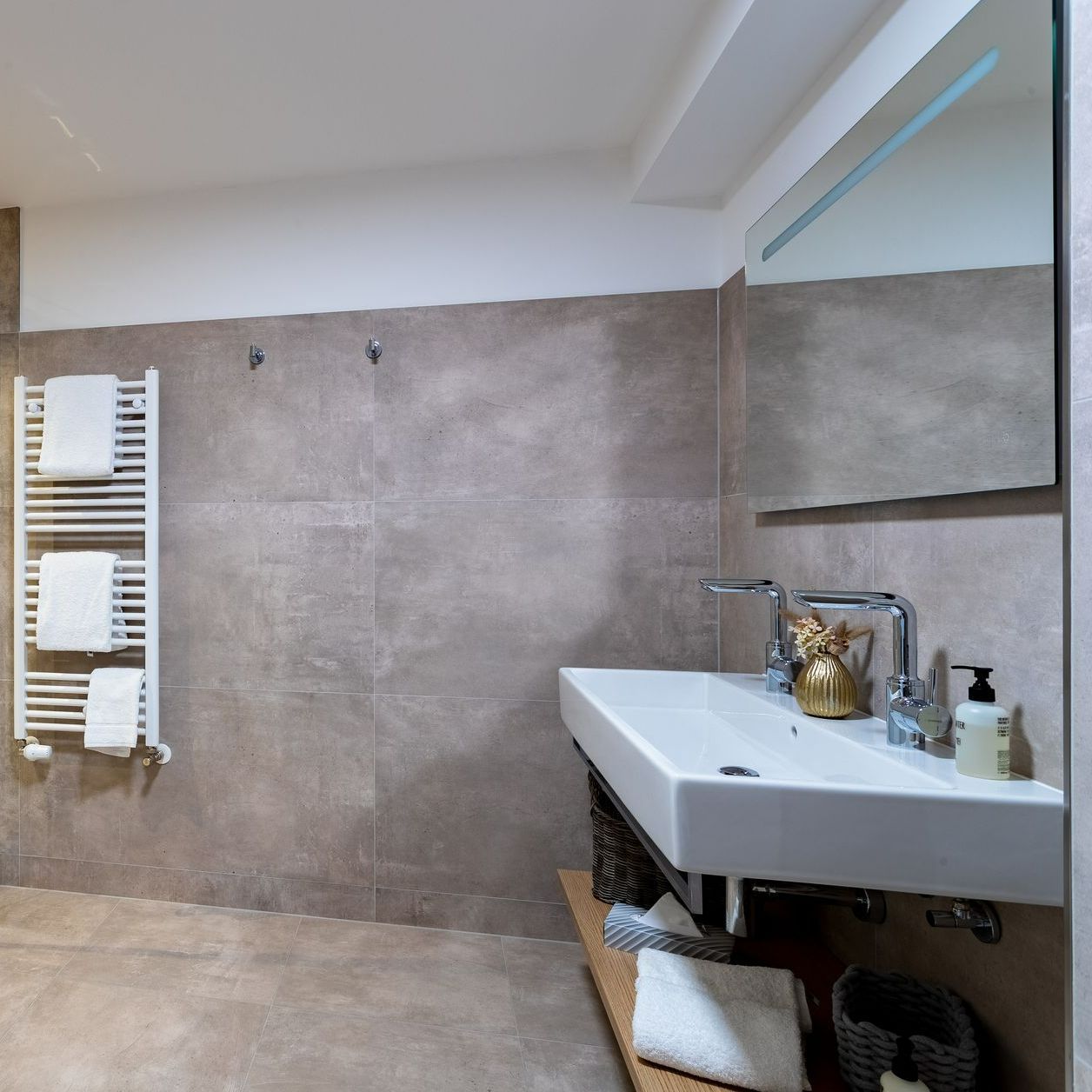 Modernes Badezimmer mit weißem Waschbecken, grauer Wand und Handtuchhalter.