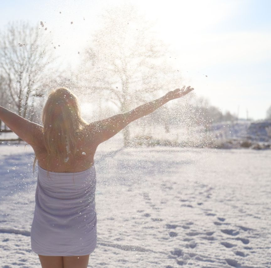 Menschen speisen in der Abenddämmerung im Freien unter Lichterketten und Bäumen.