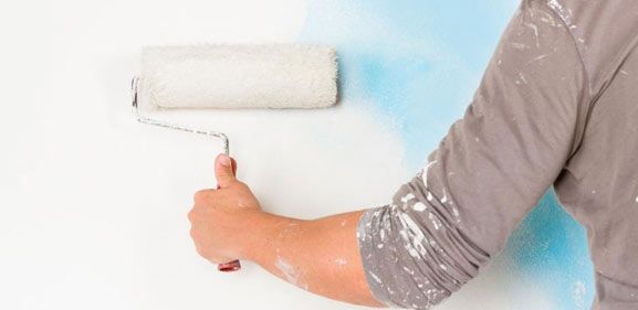Una persona está pintando una pared con un rodillo de pintura.