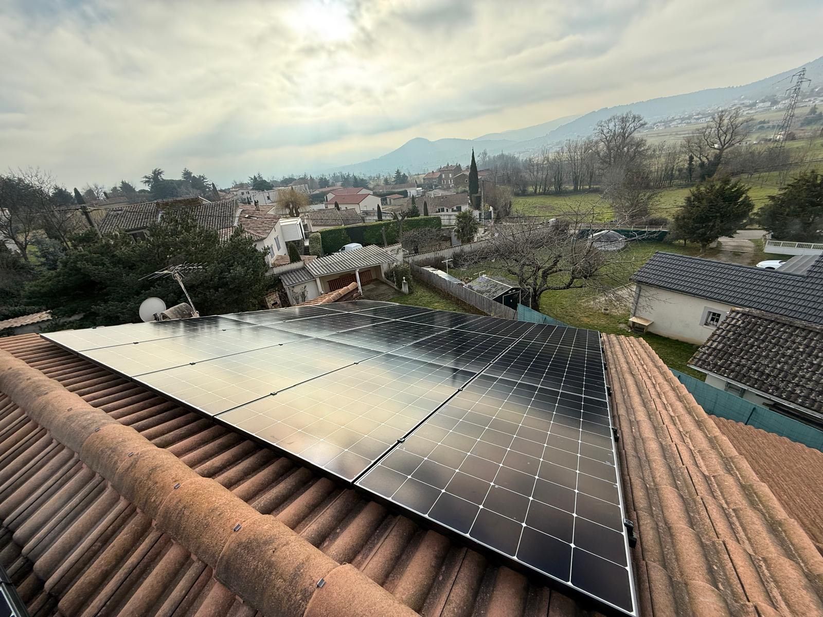 Panneaux photovoltaïques vus depuis le toit d'une maison avec une vue sur un village.