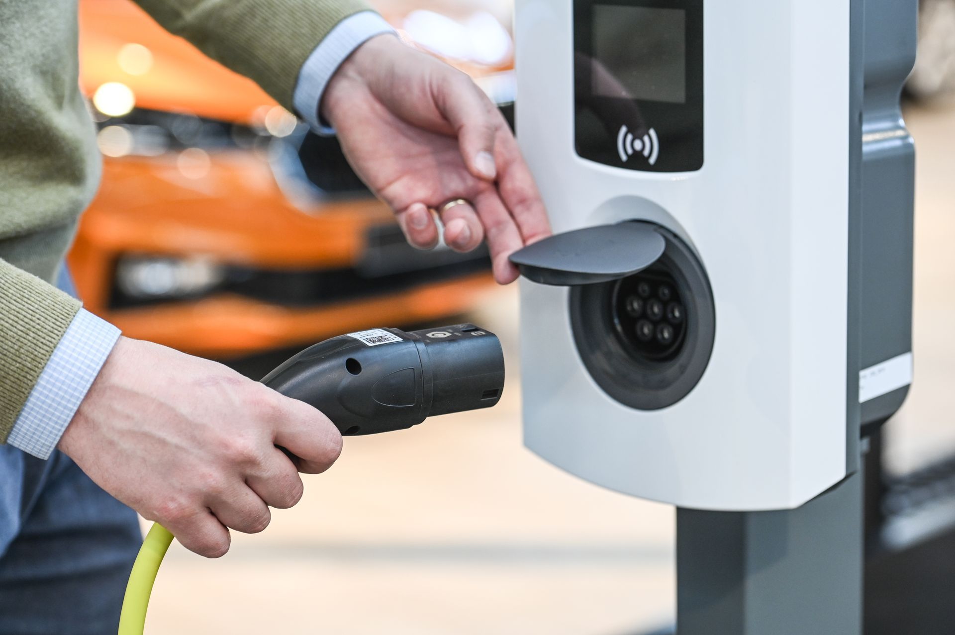 Borne de recharge électrique fonctionnelle avec individu s'apprêtant à brancher un câble.