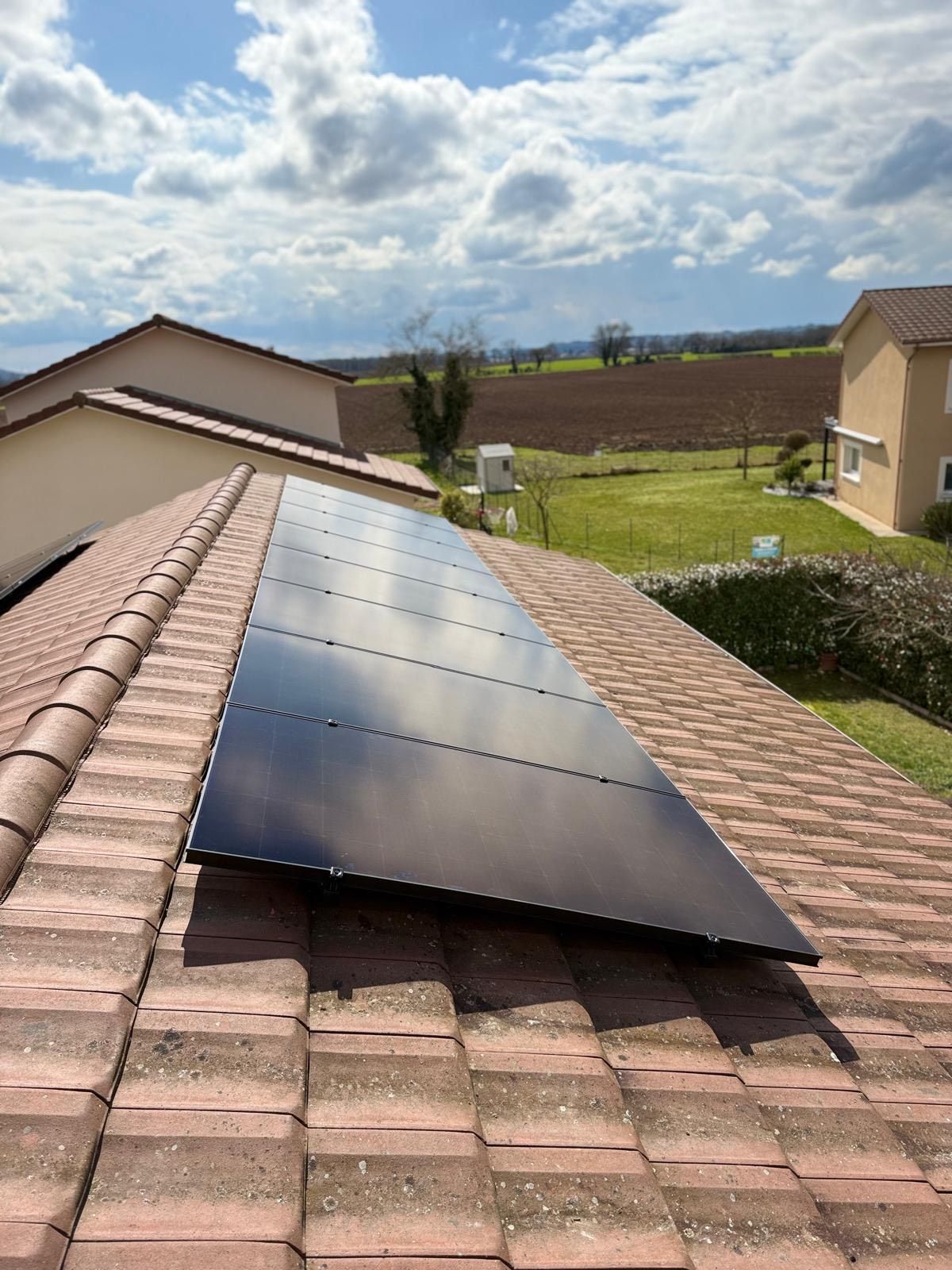 Bande panneaux solaires sur une toiture d'une maison près d'un champ.