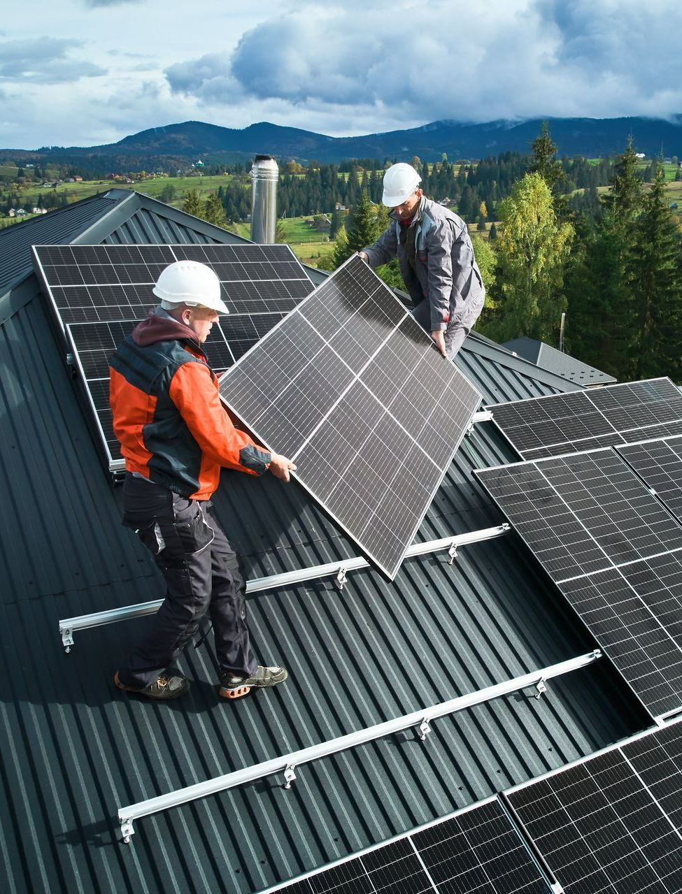Deux professionnels installant un panneau solaire sur un toit.