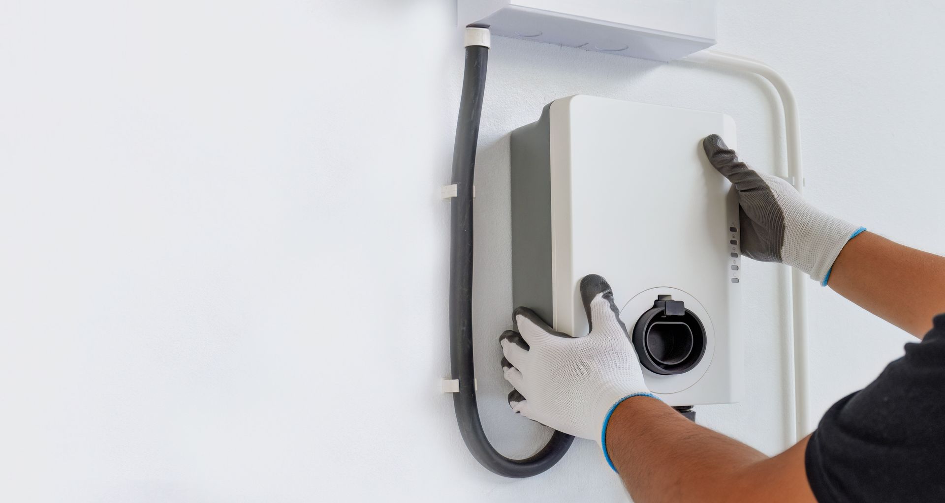 Professionnel installant une borne de recharge sur un mur.