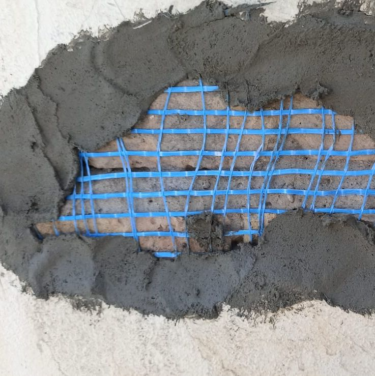 Un agujero en una pared cubierto por una malla azul.