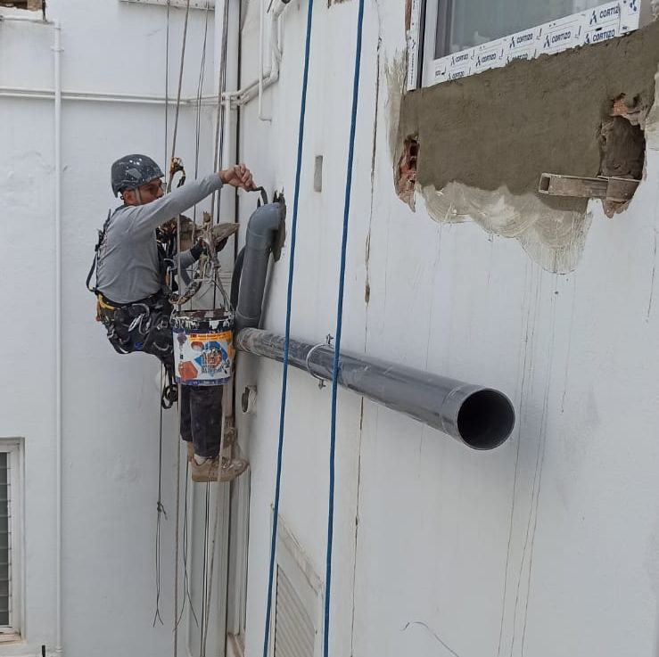 Un hombre está pintando una pared con un balde de pintura.
